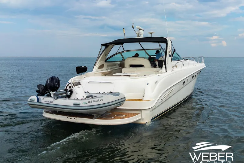 Slide: The Image of Sea Ray Sundancer 460 yacht cruising on open water, featuring a small dinghy. - 33