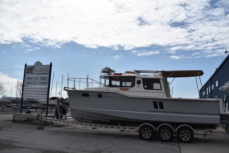 The Image of 2021 Ranger Tugs R-27 boat on trailer at marina under cloudy sky. - 0
