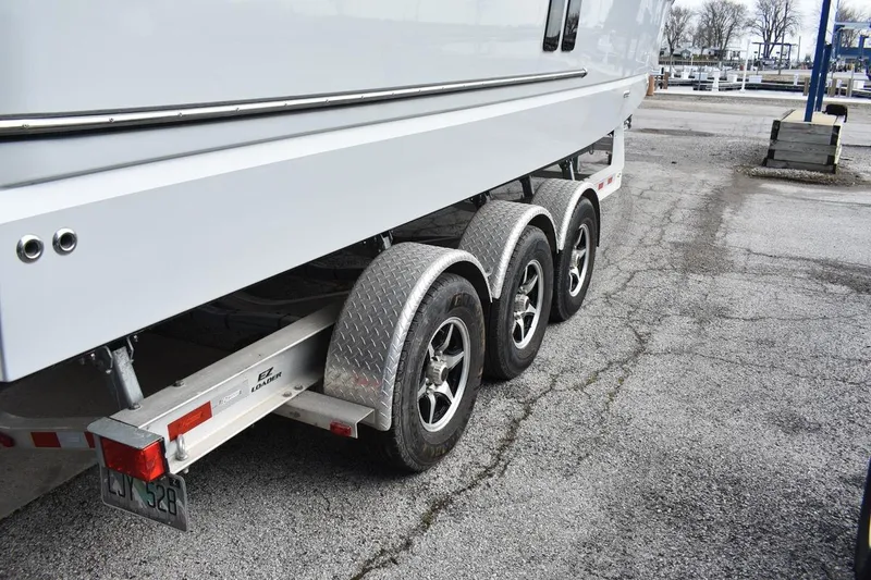 Slide: The Image of 2021 Ranger Tugs R-27 on a triple-axle trailer at a marina. - 12
