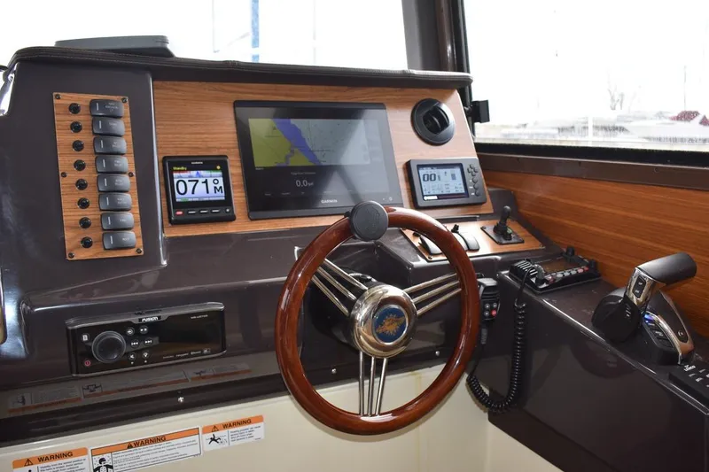 Slide: The Image of 2021 Ranger Tugs R-27 helm with navigation screens and wooden steering wheel. - 17