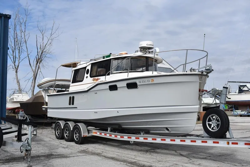 Slide: The Image of 2021 Ranger Tugs R-27 boat on a trailer in a marina setting. - 2