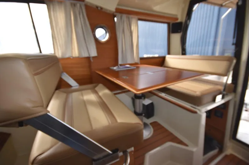 Slide: The Image of Interior of 2021 Ranger Tugs R-27 with beige seating and wooden table. - 23