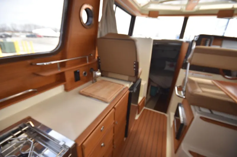 Slide: The Image of Interior of 2021 Ranger Tugs R-27, featuring a compact kitchen and cozy cabin space. - 25