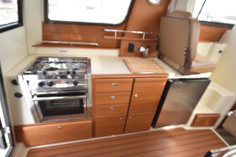 Slide: The Image of 2021 Ranger Tugs R-27 interior kitchen with stove, sink, and refrigerator. - 26