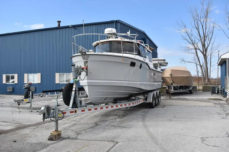Slide: The Image of 2021 Ranger Tugs R-27 boat on trailer near blue warehouse. - 3