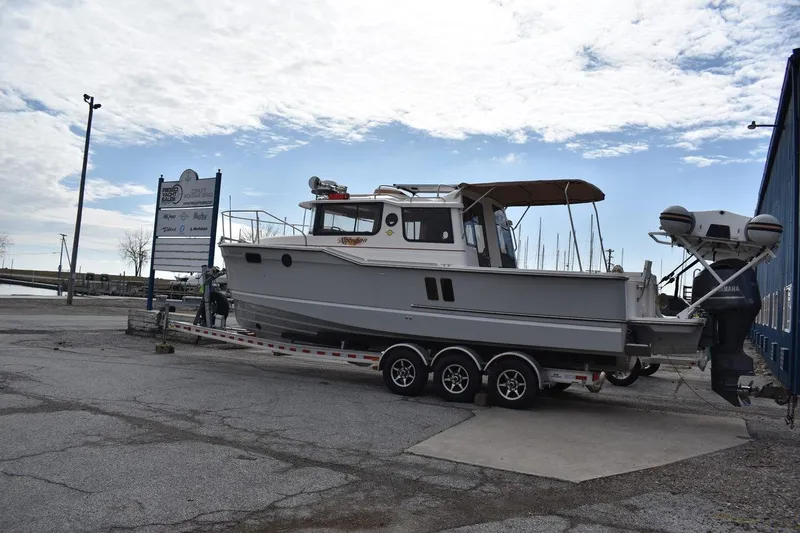 Slide: The Image of 2021 Ranger Tugs R-27 boat on trailer at marina, under cloudy sky. - 8