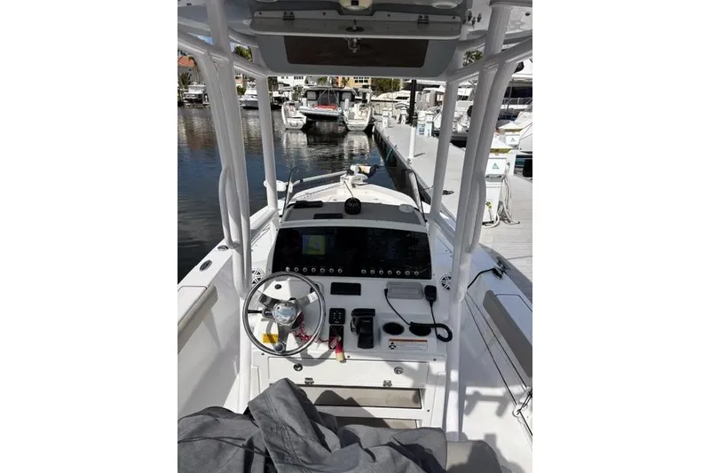 Slide: The Image of 2022 Sportsman Masters 227 Bay Boat cockpit with steering wheel and controls at marina. - 10