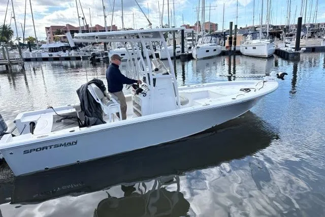 Slide: The Image of 2022 Sportsman Masters 227 Bay Boat docked in marina with a person at the helm. - 11