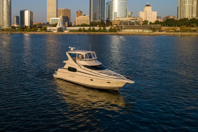 Slide: The Image of 2003 Silverton 410 Sport Bridge yacht on water with city skyline backdrop. - 19
