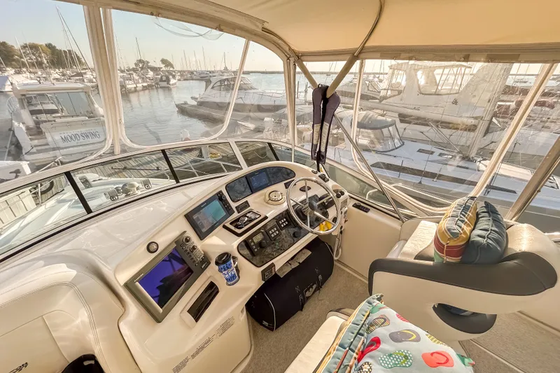 Slide: The Image of Interior view of 2003 Silverton 410 Sport Bridge yacht helm with marina backdrop. - 27
