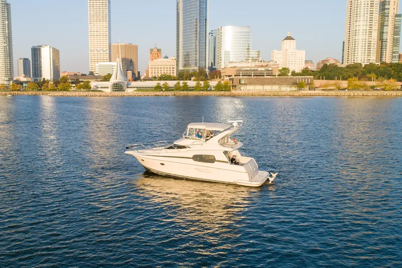 Slide: The Image of 2003 Silverton 410 Sport Bridge yacht cruising near city skyline on calm waters. - 3