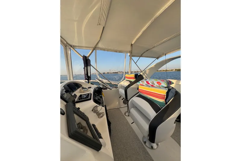 Slide: The Image of 2003 Silverton 410 Sport Bridge interior with helm, colorful cushions, and ocean view. - 32