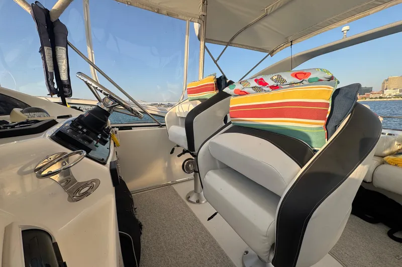 Slide: The Image of 2003 Silverton 410 Sport Bridge helm with striped cushions and steering wheel, overlooking water. - 33