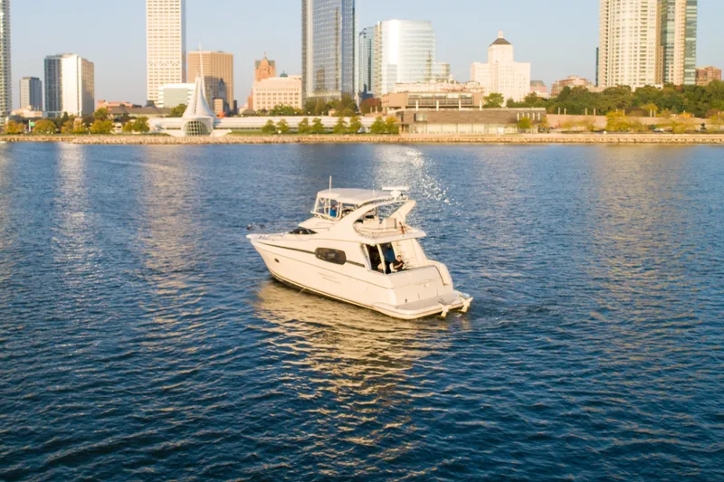 Slide: The Image of 2003 Silverton 410 Sport Bridge yacht cruising near city skyline on calm water. - 4