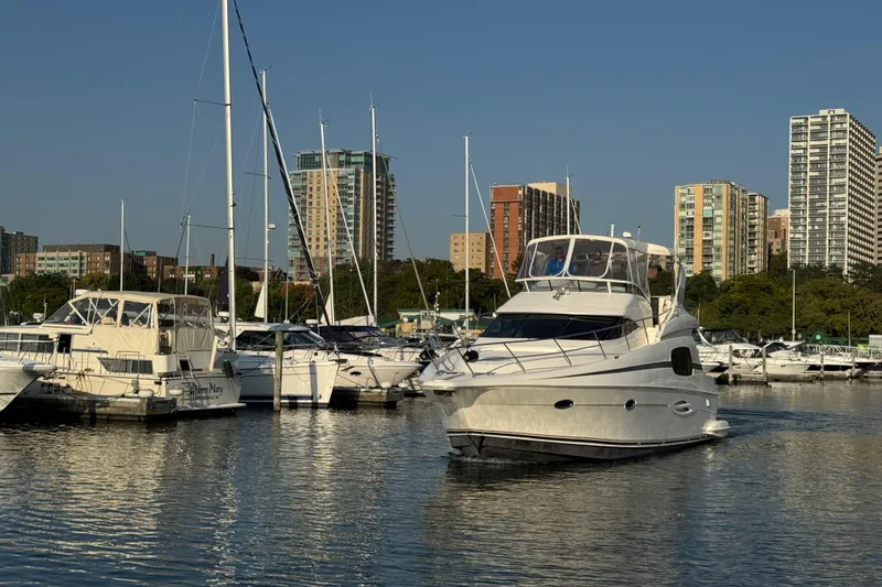 Slide: The Image of 2003 Silverton 410 Sport Bridge yacht in urban marina with city skyline backdrop. - 51
