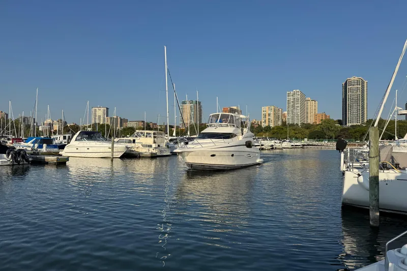 Slide: The Image of 2003 Silverton 410 Sport Bridge yacht docked in a marina with city skyline backdrop. - 52