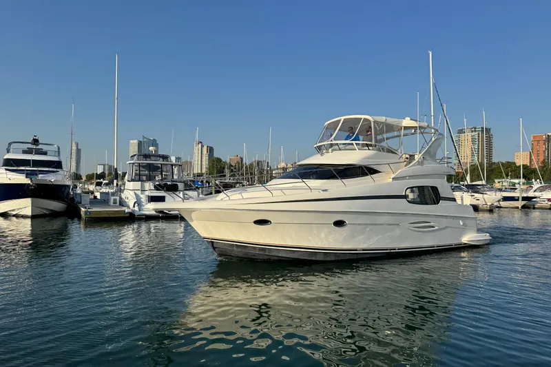 Slide: The Image of 2003 Silverton 410 Sport Bridge yacht docked in a marina under clear blue skies. - 55