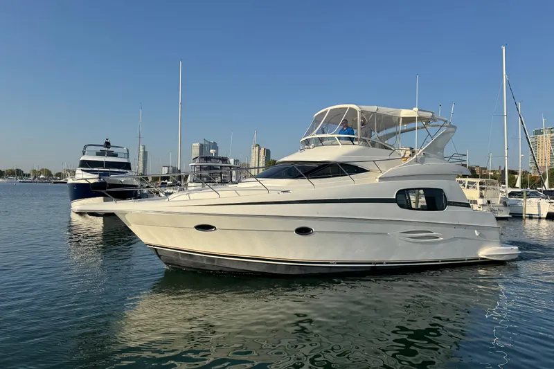 Slide: The Image of 2003 Silverton 410 Sport Bridge yacht docked in a marina under clear blue skies. - 56