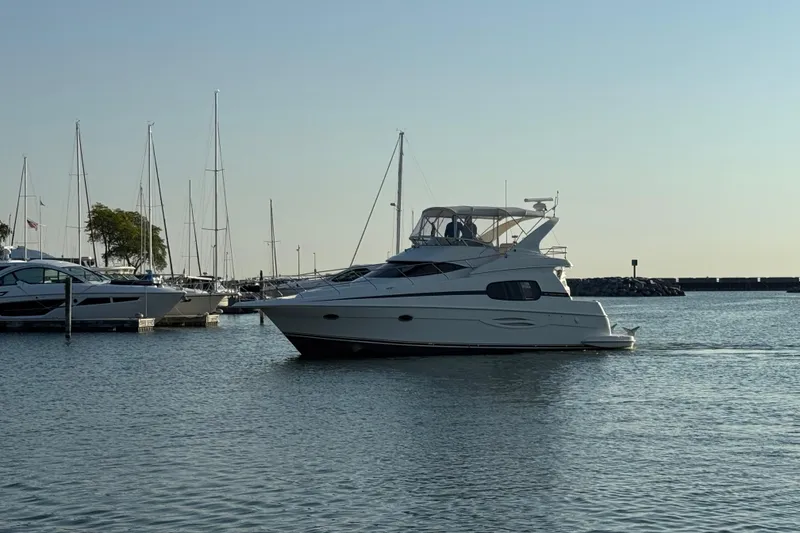 Slide: The Image of 2003 Silverton 410 Sport Bridge yacht cruising in a marina with sailboats. - 58