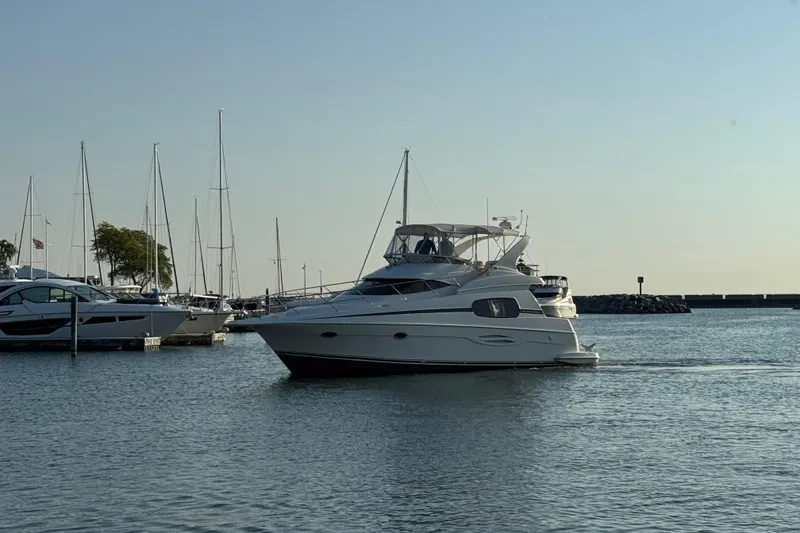 Slide: The Image of 2003 Silverton 410 Sport Bridge yacht docked in a serene marina setting. - 59