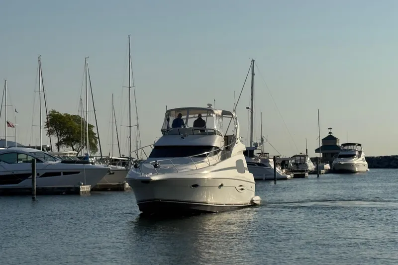 Slide: The Image of 2003 Silverton 410 Sport Bridge yacht navigating a marina with sailboats in the background. - 60