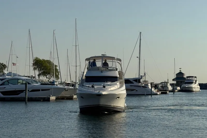 Slide: The Image of 2003 Silverton 410 Sport Bridge yacht navigating marina with sailboats in background. - 61