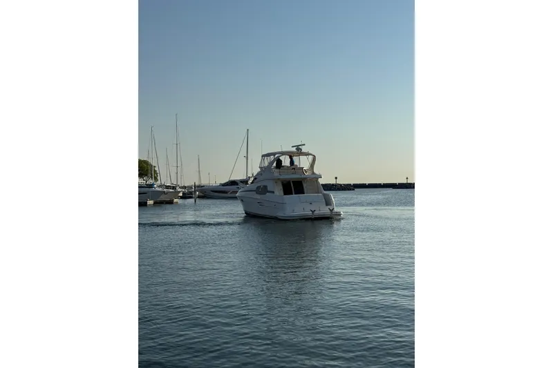 Slide: The Image of 2003 Silverton 410 Sport Bridge yacht cruising in a serene marina setting. - 65