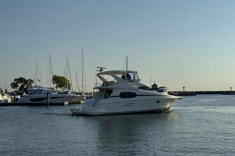 Slide: The Image of 2003 Silverton 410 Sport Bridge yacht cruising in a marina with sailboats. - 66