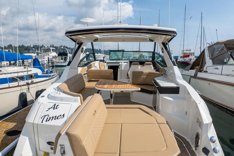 Slide: The Image of 2019 Sea Ray Sundancer 320 yacht interior with tan seating and wooden table at marina. - 10