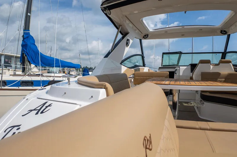 Slide: The Image of 2019 Sea Ray Sundancer 320 yacht interior with beige seating and wooden table, docked at marina. - 11