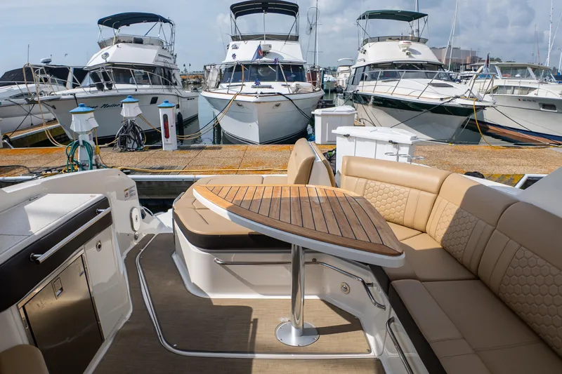 Slide: The Image of 2019 Sea Ray Sundancer 320 interior with elegant seating and wooden table, docked at marina. - 17
