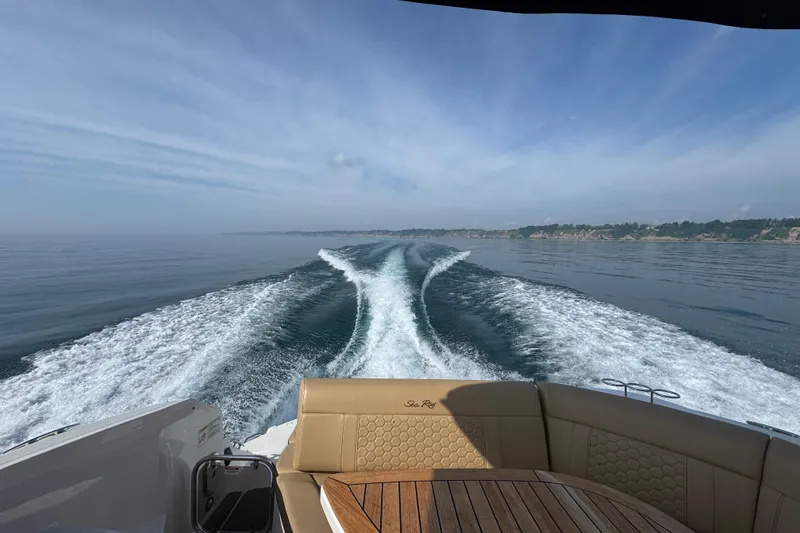Slide: The Image of 2019 Sea Ray Sundancer 320 cruising, leaving a wake on calm waters under a clear sky. - 9