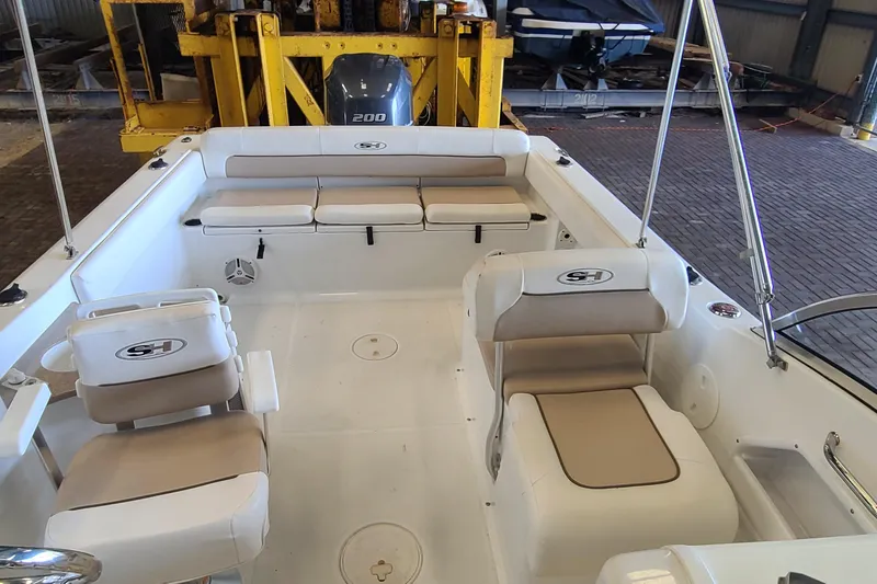 Slide: The Image of 2013 Sea Hunt Escape 234 LE boat interior with seating and motor in a storage facility. - 20