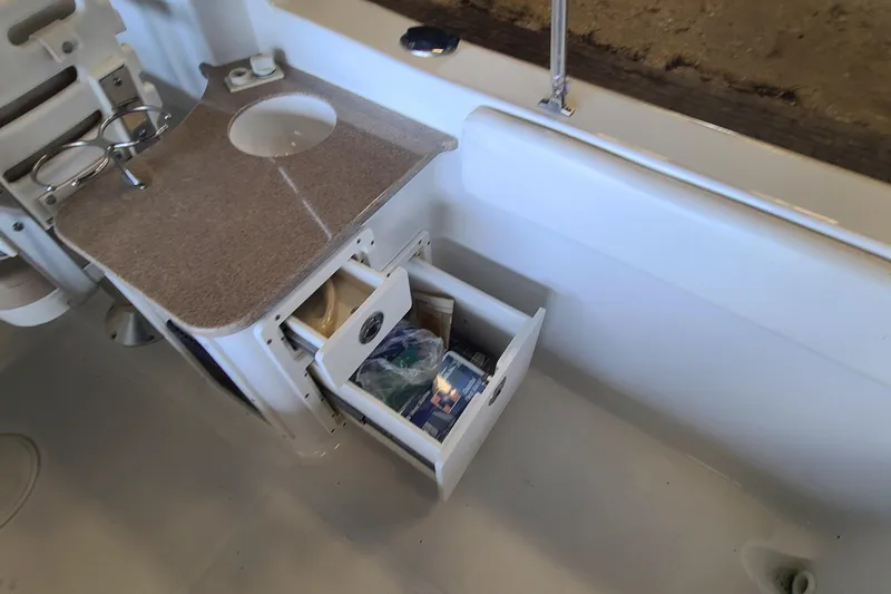 Slide: The Image of Interior of 2013 Sea Hunt Escape 234 LE boat with open storage drawers. - 24