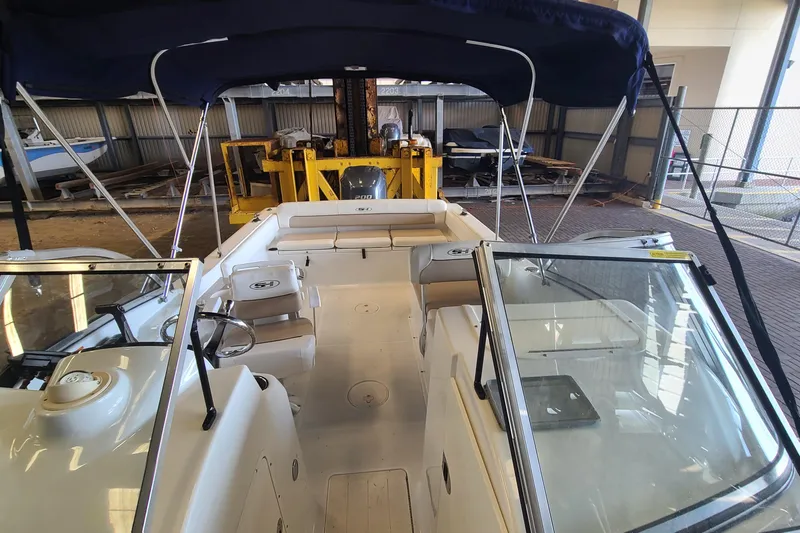 Slide: The Image of 2013 Sea Hunt Escape 234 LE boat interior with seating and steering wheel in a storage facility. - 7