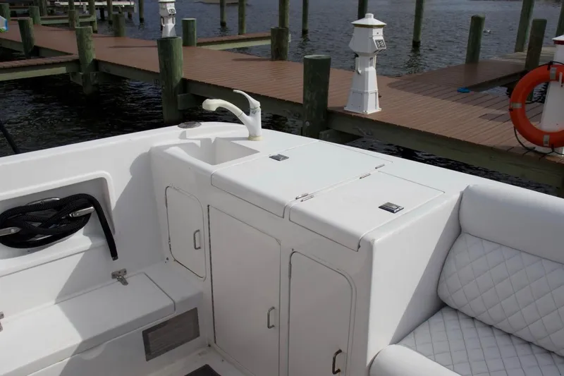 Slide: The Image of 2002 McKinna 57 Pilothouse yacht deck with sink, storage, and cushioned seating by the dock. - 39