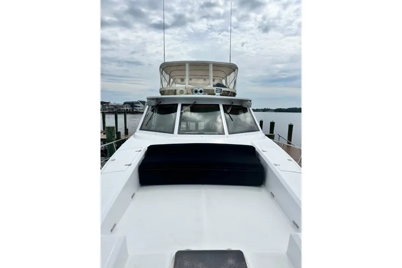 Slide: The Image of 2002 McKinna 57 Pilothouse yacht docked, showcasing spacious deck and pilothouse under cloudy sky. - 8