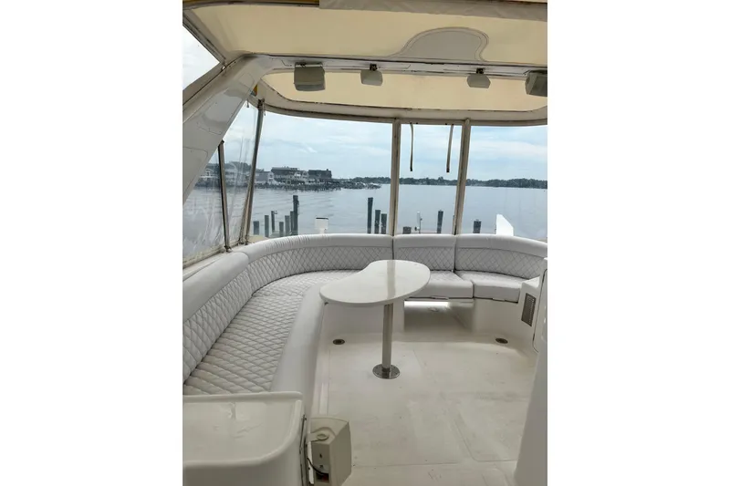 Slide: The Image of 2002 McKinna 57 Pilothouse yacht interior with curved seating and table, overlooking serene waterfront. - 9
