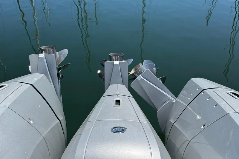 Slide: The Image of Triple outboard motors on a 2025 Intrepid 50 Evolution boat, reflecting in calm water. - 5