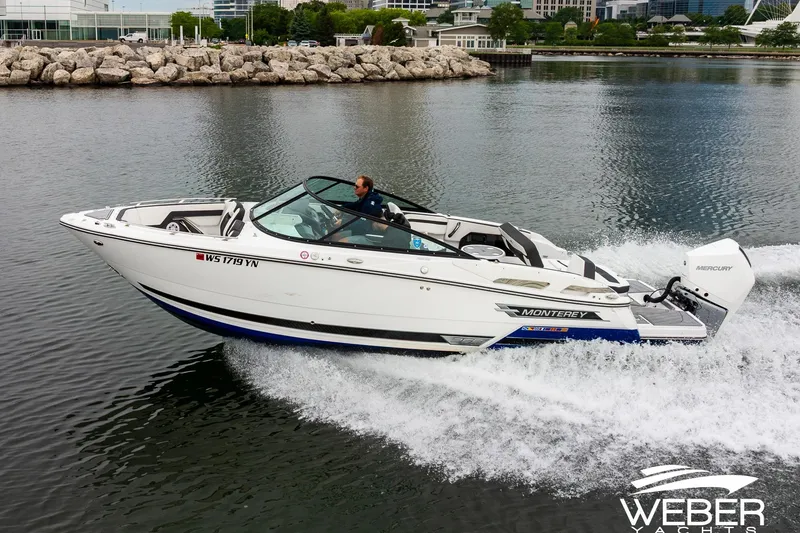 The Image of 2023 Monterey 255SS Super Sport boat cruising on a calm lake near a rocky shoreline. - 0