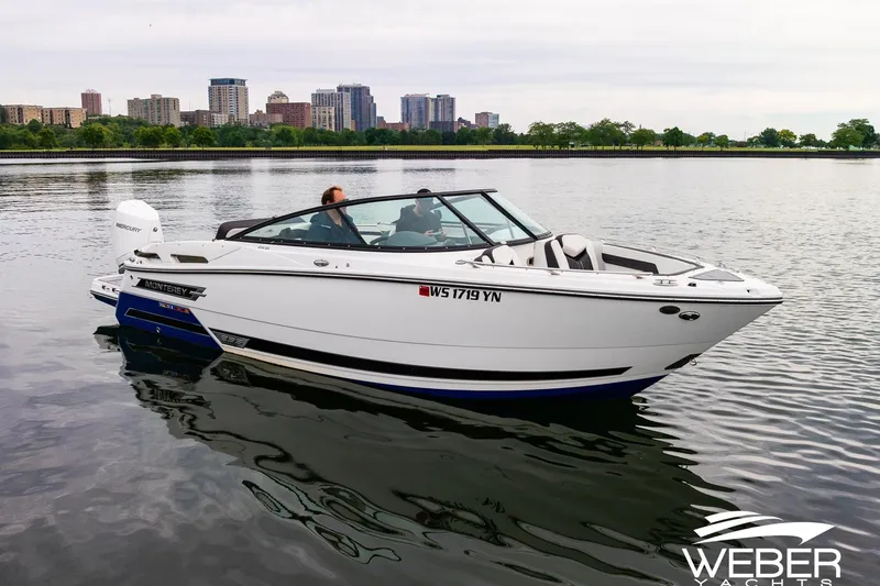 Slide: The Image of 2023 Monterey 255SS Super Sport boat on calm water with city skyline backdrop. - 11