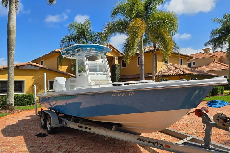 The Image of 2014 Everglades 243 Center Console boat on trailer, parked in tropical driveway. - 1