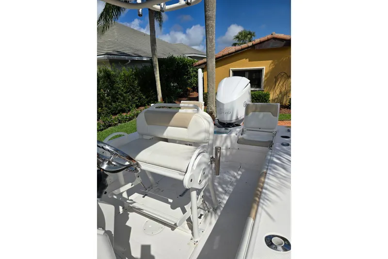 Slide: The Image of 2014 Everglades 243 Center Console boat with seating and outboard motor in a sunny yard. - 10