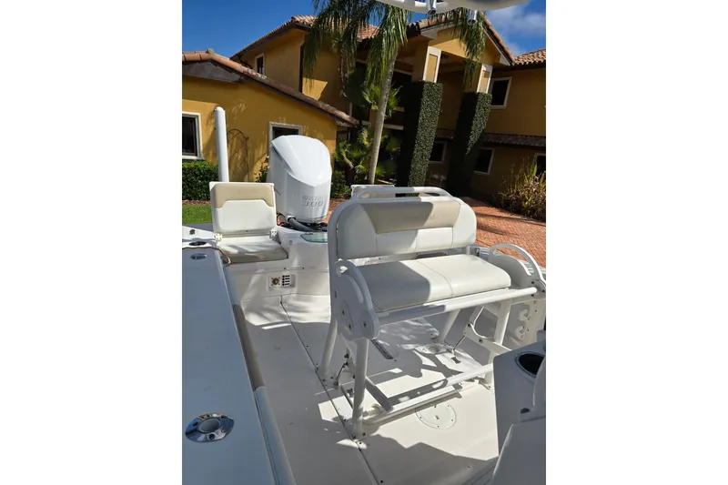 Slide: The Image of 2014 Everglades 243 Center Console boat with seating, parked near a house. - 11