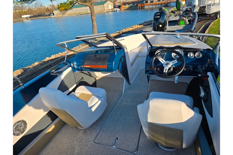 Slide: The Image of 2016 Glastron GT 185 boat interior with steering wheel, seats, and waterfront view. - 10