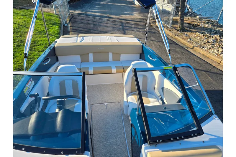 Slide: The Image of 2016 Glastron GT 185 boat interior with seating and steering wheel, docked by the water. - 18