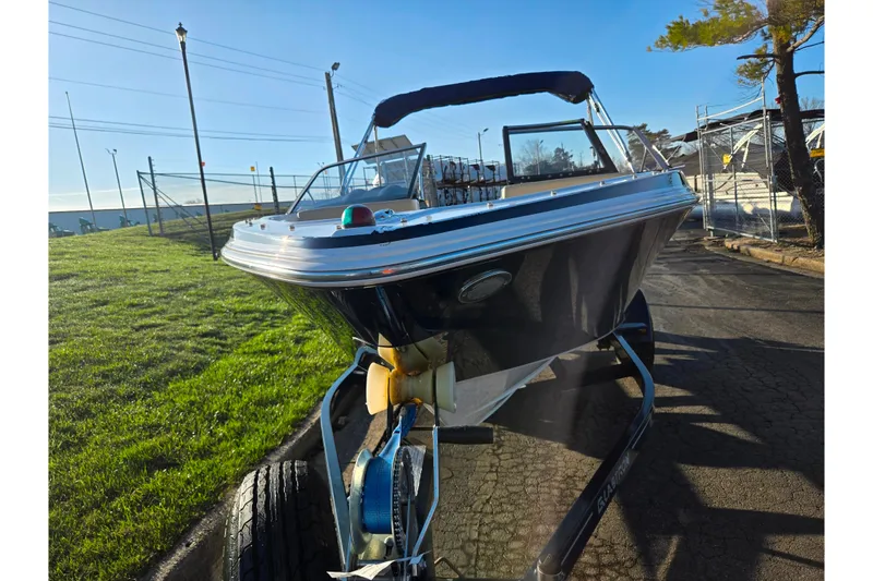 Slide: The Image of 2016 Glastron GT 185 boat on trailer, parked outdoors under clear blue sky. - 6