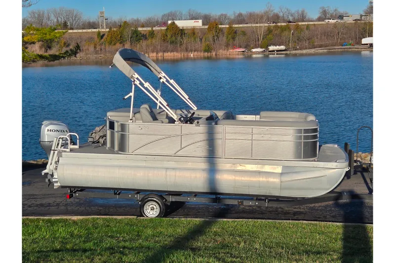 The Image of 2021 Bennington S 20 L-Bench pontoon boat on trailer by a lake. - 0