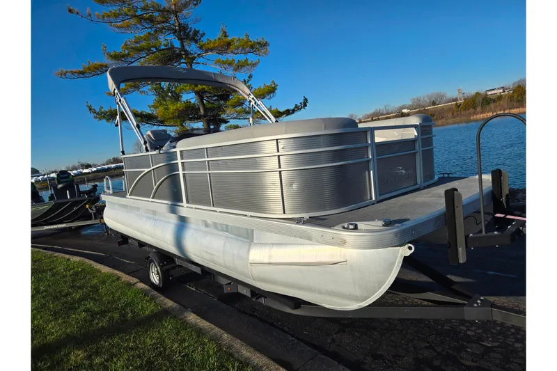 Slide: The Image of 2021 Bennington S 20 L-Bench pontoon boat on trailer by a lake. - 8
