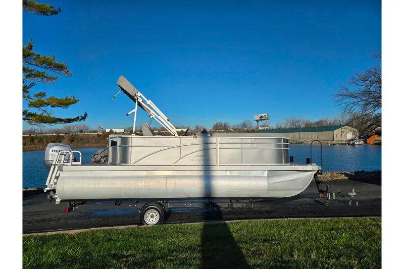Slide: The Image of 2021 Bennington S 20 L-Bench pontoon boat on trailer by a lake. - 9